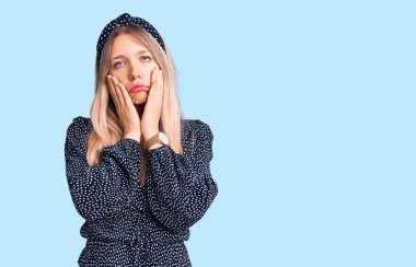 Genç, güzel, sarışın bir kadın günlük kıyafetler giyiyor. Yorgun eller, yüzünü kapatıyor. Depresyon ve üzüntü yaşıyor. 