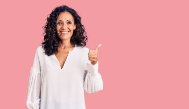 Orta yaşlı, güzel bir kadın, sıradan bir kazak giyiyor ve elleriyle mutlu bir jest yapıyor. Kameraya bakıp başarıyı gösteren ifade. 