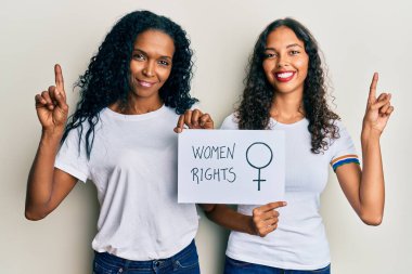 Afrika kökenli Amerikalı anne ve kız ellerinde kadın hakları afişi tutarken bir fikir ya da soruyla şaşırdılar. 