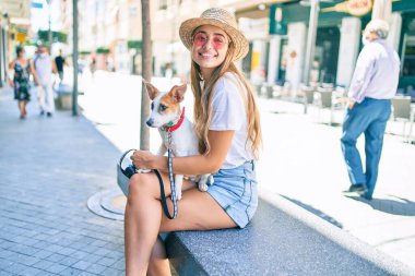 Genç, güzel, sarışın bir kadın bir yaz günü köpeği gezdirirken bankta oturuyor.