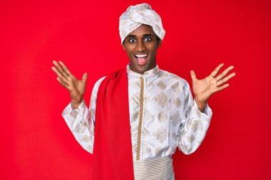 Gelenek giyinmiş yakışıklı Hintli adam Sherwani sari kıyafetleri giyiyor. Çılgınlığı kutluyor ve başarıya hayret ediyor. Kolları havada ve gözleri açık, heyecanlı bir şekilde bağırıyor. Kazanan konsept 