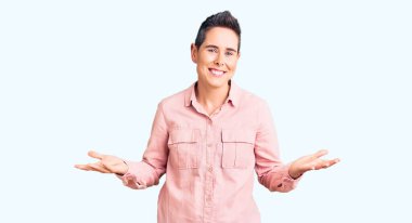 Kısa saçlı, günlük kıyafetler giyen, gülümseyen, iki elini de açık gösteren, sunan ve reklam karşılaştırma ve denge sağlayan genç bir kadın. 