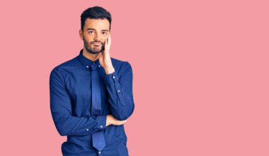 İş kıyafetleri giyen genç, yakışıklı İspanyol adam kollarını kavuşturup depresyondan sıkılmış ve yorgun görünüyor.. 