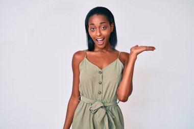 Genç Afro-Amerikan kadın, günlük giysiler giyip neşeli bir şekilde gülümseyerek el ele tutuşup kameraya bakıyor.. 