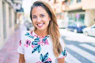 Genç İspanyol kadın gülümseyerek şehirde mutlu mesut duruyor.