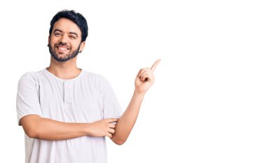 Gündelik kıyafetler giyen genç İspanyol adam gülümsüyor mutlu bir şekilde elini ve parmağını yana uzatıyordu. 