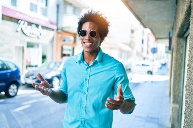 Genç, yakışıklı, Afro-Amerikan bir adam. Günlük kıyafetler ve güneş gözlüğü takıyor. Mutlu gülümsüyor. Yüzünde gülümsemeyle kasaba caddesinde yürürken.