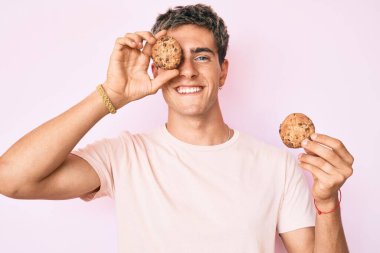 Elinde kurabiyeyle gülümseyen yakışıklı bir genç adam yüzünde güzel bir gülümsemeyle. diş gösterme. 