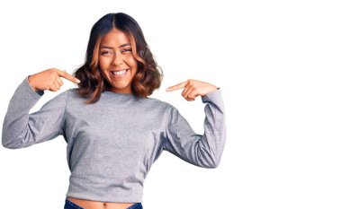 Genç, güzel, melez, günlük kıyafetler giyen, kendine güvenen, gülümseyen, kendini gururlu ve mutlu gösteren bir kadın.. 