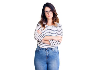 Gündelik kıyafetler giyen, gözlüklü, kuşkucu ve gergin genç ve güzel esmer bir kadın. Yüzünde çapraz kollarla onaylamayan bir ifade var. negatif kişi. 