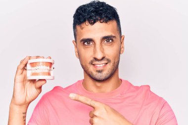 Takma dişleri olan genç İspanyol adam mutlu bir şekilde elini ve parmağını gösterdi. 