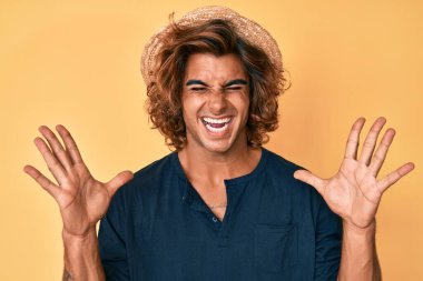 Yaz şapkası takan genç İspanyol adam başarı için deli ve çılgınlığı kutluyor kollarını kaldırmış ve gözlerini kapatmış heyecanla bağırıyor. Kazanan konsept 