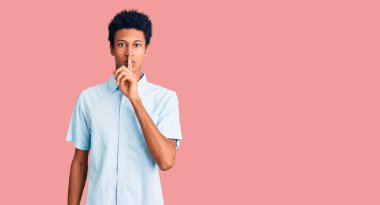 Gündelik giysiler giymiş genç Afro-Amerikan bir adam sessiz olmak istiyor. sessizlik ve gizli konsept. 