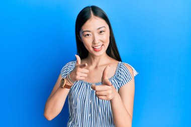 Sıradan çizgili tişört giyen genç Çinli kadın kameraya mutlu ve komik yüzlü parmaklar gösteriyor. iyi enerji ve titreşimler. 