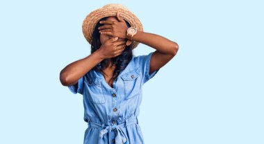 Yazlık şapka takan genç Hintli kız gözlerini ve ağzını elleriyle kapatıyor, şaşırmış ve şok olmuş. duygu gizleme 