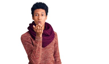 Genç Afro-Amerikan erkek, günlük kışlık süveter ve fular giyip kameraya bakarken havada el ele öpüşmek güzel ve seksi oluyor. aşk ifadesi. 