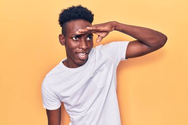 Genç, Afro-Amerikan bir adam günlük giysiler giyiyor çok mutlu ve gülümsüyor başlarını kaldırıp uzaklara bakıyor. arama kavramı. 