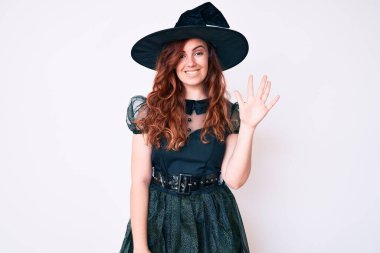 Cadılar Bayramı kostümü giymiş genç ve güzel bir kadın gülümseyerek kendinden emin ve mutlu gülümserken beş numarayı işaret ediyor.. 