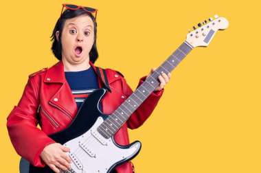 Down sendromlu esmer kadın elektro gitar çalıyor. Korkmuş ve ağzı açık bir şekilde şaşırmış. 