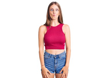 Zarif bir yaz gömleği giyen genç ve güzel bir sarışın dudaklarıyla balık suratı yapan çılgın ve komik bir jest yapan. Komik ifade. 