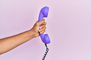 İspanyol el, izole edilmiş pembe arka planda klasik telefon tutuyor..