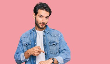 Gündelik giysiler giyen genç İspanyol adam saati, sabırsızlığı ve gecikmeyi izlemek için acele ediyor. 