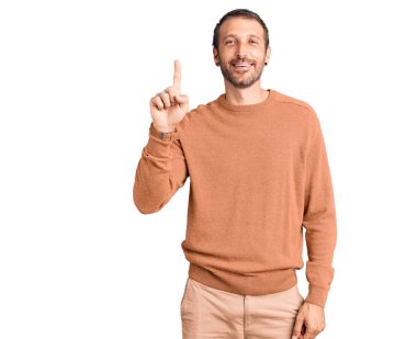 Gündelik kıyafetler giyen genç yakışıklı bir numarayı gösterip işaret ederken kendinden emin ve mutlu bir şekilde gülümsüyor.. 