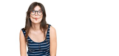 Gündelik kıyafetler ve gözlük takan genç beyaz bir kız dudaklarıyla balık suratı yapıyor, çılgınca ve komik bir jest. Komik ifade. 