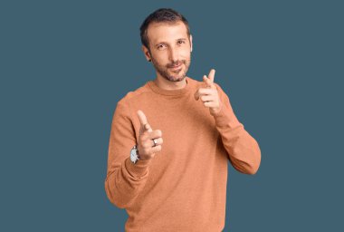 Gündelik giysiler giymiş genç yakışıklı adam mutlu ve komik yüzüyle kamerayı işaret ediyor. iyi enerji ve titreşimler. 