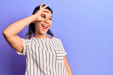 Gündelik kıyafetler giyen, gülümseyen, mutlu bir genç kadın el pençe divan duran parmaklarıyla işaret veriyor. 