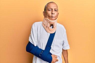 Servikal tasma takan ve kol askısı takan yakışıklı, dudaklı balık suratı yapan, çılgın ve komik bir jest. Komik ifade. 