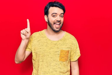 Bir fikir veya soruyla gülümseyen gündelik kıyafetler giyen genç İspanyol adam, bir numara, mutlu bir yüzle işaret ediyor. 