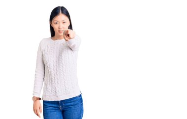 Genç ve güzel Çinli kadın, sıradan bir süveter giyerek kameraya kızgın ve sinirli bir şekilde bakıyor. 