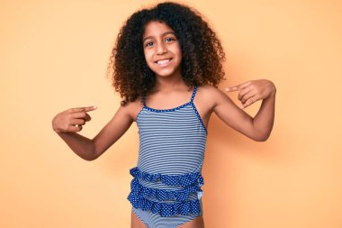 Kıvırcık saçlı, mayo giyen, kendine güvenen, gülümseyen, kendini gururlu ve mutlu gösteren Afro-Amerikan çocuğu.. 