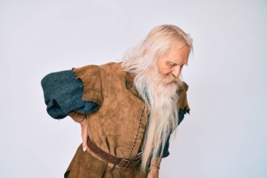 Gri saçlı ve uzun sakallı yaşlı bir adam. Geleneksel Viking kostümü giyiyor. Sırt ağrısı çekiyor. 