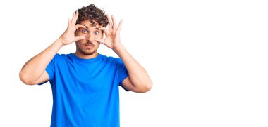 Kıvırcık saçlı, sıradan kıyafetler giyen, parmaklarıyla gözlerini açmaya çalışan, uykulu ve yorgun, sabah yorgunluğu çeken genç bir adam. 