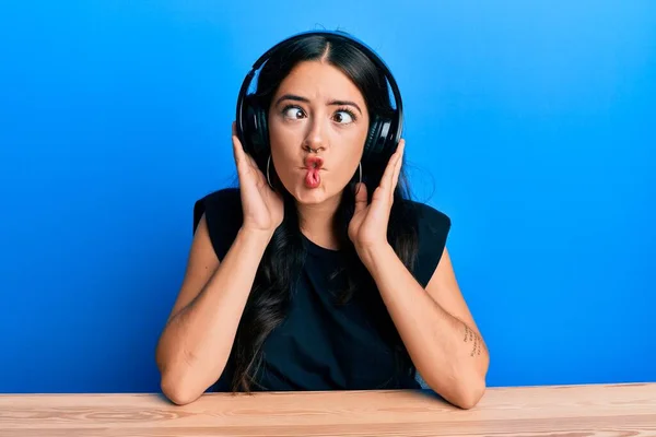 Όμορφη Μελαχρινή Νεαρή Γυναίκα Ακούγοντας Μουσική Χρησιμοποιώντας Ακουστικά Κάνοντας Πρόσωπο — Φωτογραφία Αρχείου