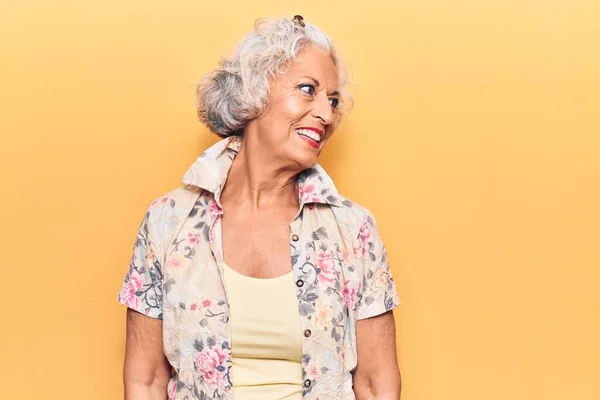 Senior grey-haired woman wearing casual clothes looking away to side with smile on face, natural expression. laughing confident.