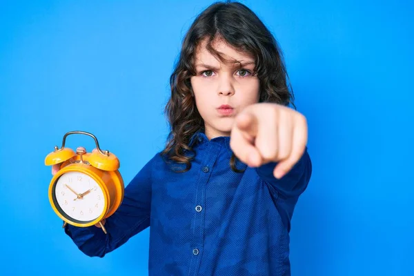 Lindo Niño Hispano Con Pelo Largo Sosteniendo Despertador Señalando Con —  Fotos de Stock