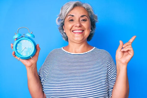 Ältere Hispanische Frau Mit Wecker Lächelt Glücklich Und Zeigt Mit — Stockfoto