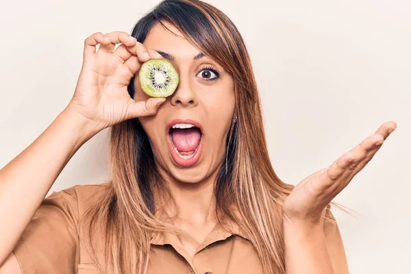 Jovem Mulher Bonita Segurando Kiwi Sobre Olho Celebrando Realização Com — Fotografia de Stock