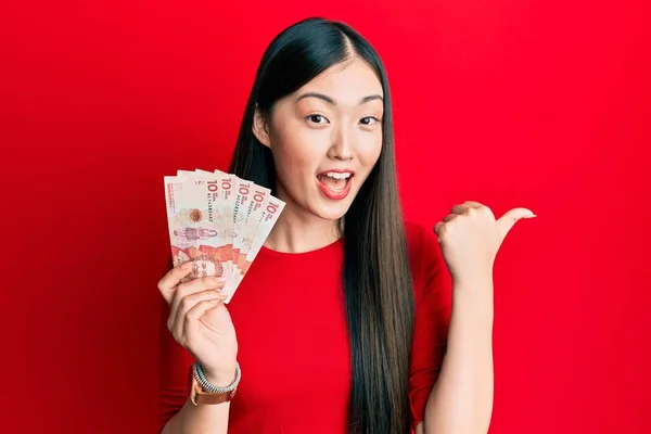 Jonge Chinese Vrouw Met Colombiaanse Pesos Bankbiljetten Wijzen Duim Naar — Stockfoto
