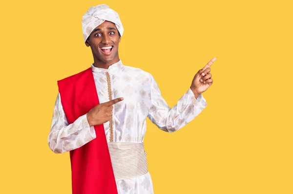 전통적 샤르와 아프리카잘생긴 남자가 웃으며 손가락을 좌우로 향하고 카메라를 바라본다 — 스톡 사진