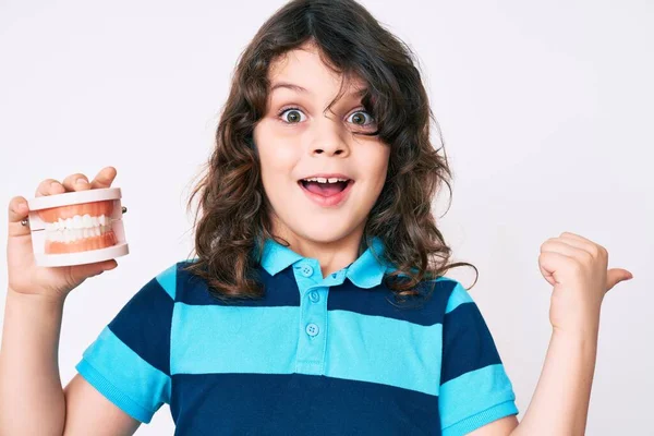 Lindo Niño Hispano Con Pelo Largo Sosteniendo Dentadura Postiza Apuntando —  Fotos de Stock