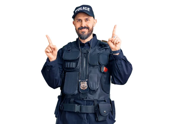 身穿警服的年轻英俊男子面带微笑 自信地用手指指向不同的方向 复制广告空间 — 图库照片
