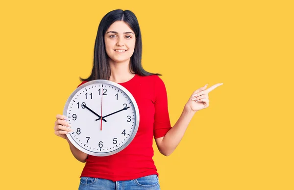 Young Beautiful Girl Holding Clock Smiling Happy Pointing Hand Finger — Stock Photo, Image