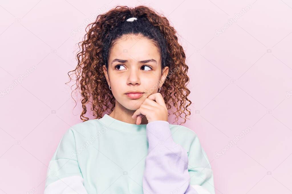 Beautiful kid girl with curly hair wearing casual clothes serious face thinking about question with hand on chin, thoughtful about confusing idea 