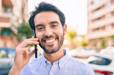 Genç İspanyol adam gülümsüyor. Şehirdeki akıllı telefondan konuşuyor..