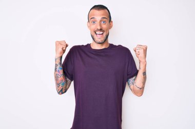 Gündelik giysiler giymiş genç yakışıklı adam kollarını kaldırıp, gözlerini açarak başarıyı kutluyor ve şaşırıyor. Kazanan konsept. 