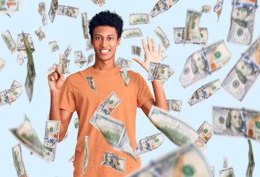 Genç Afro-Amerikalı günlük kıyafetler giymiş altı numarayı gösterip işaret ederken kendinden emin ve mutlu bir şekilde gülümsüyor..